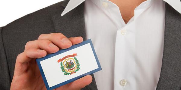Man holding a business card with the West Virginia coat of arms